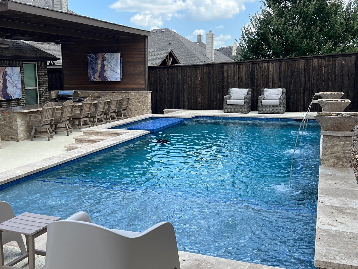 Pool with blue glass tile, cascading bowl fountains and a covered outdoor kitchen with bar seating